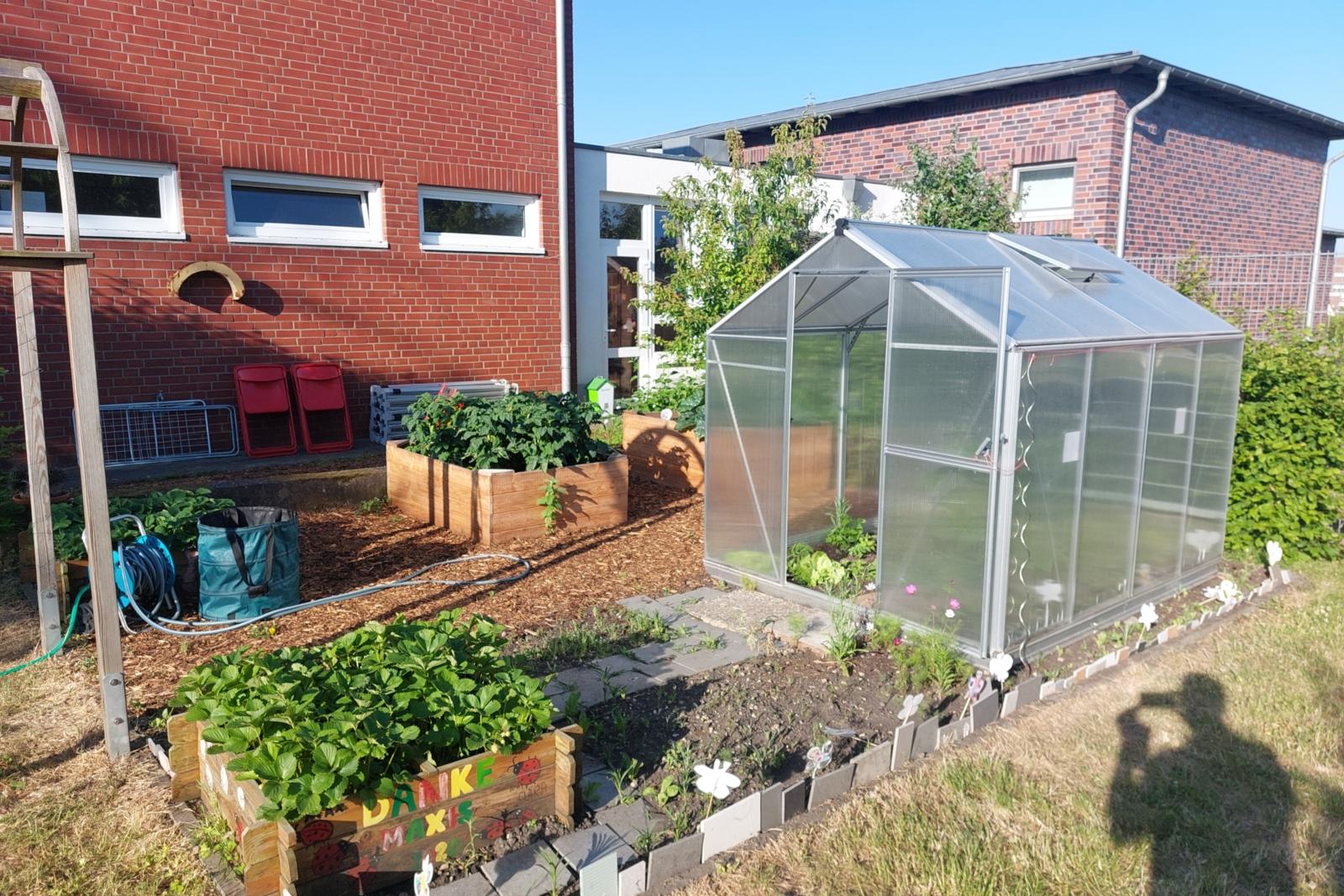 Außengelände Kita- Im Nutzgarten steht ein kleines Gewächshaus